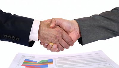 Executive shaking hands over strategic documents